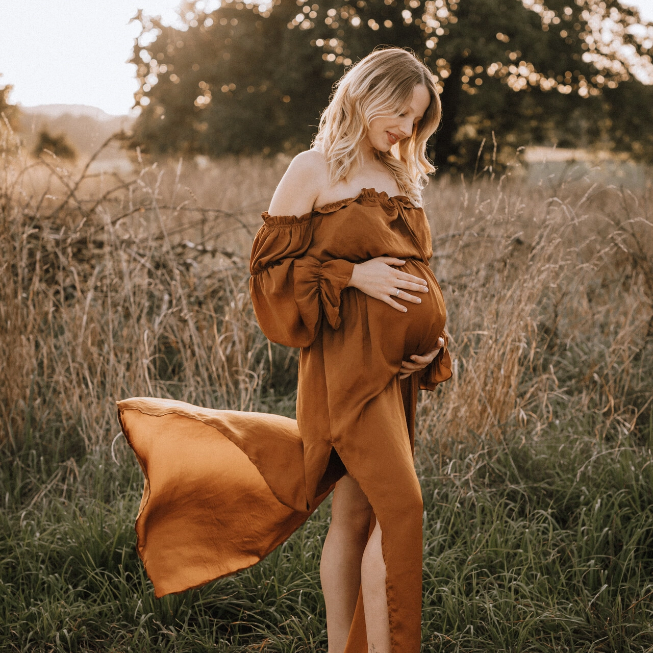 Mutter im Kleid legt ihre Hände auf den Babybauch