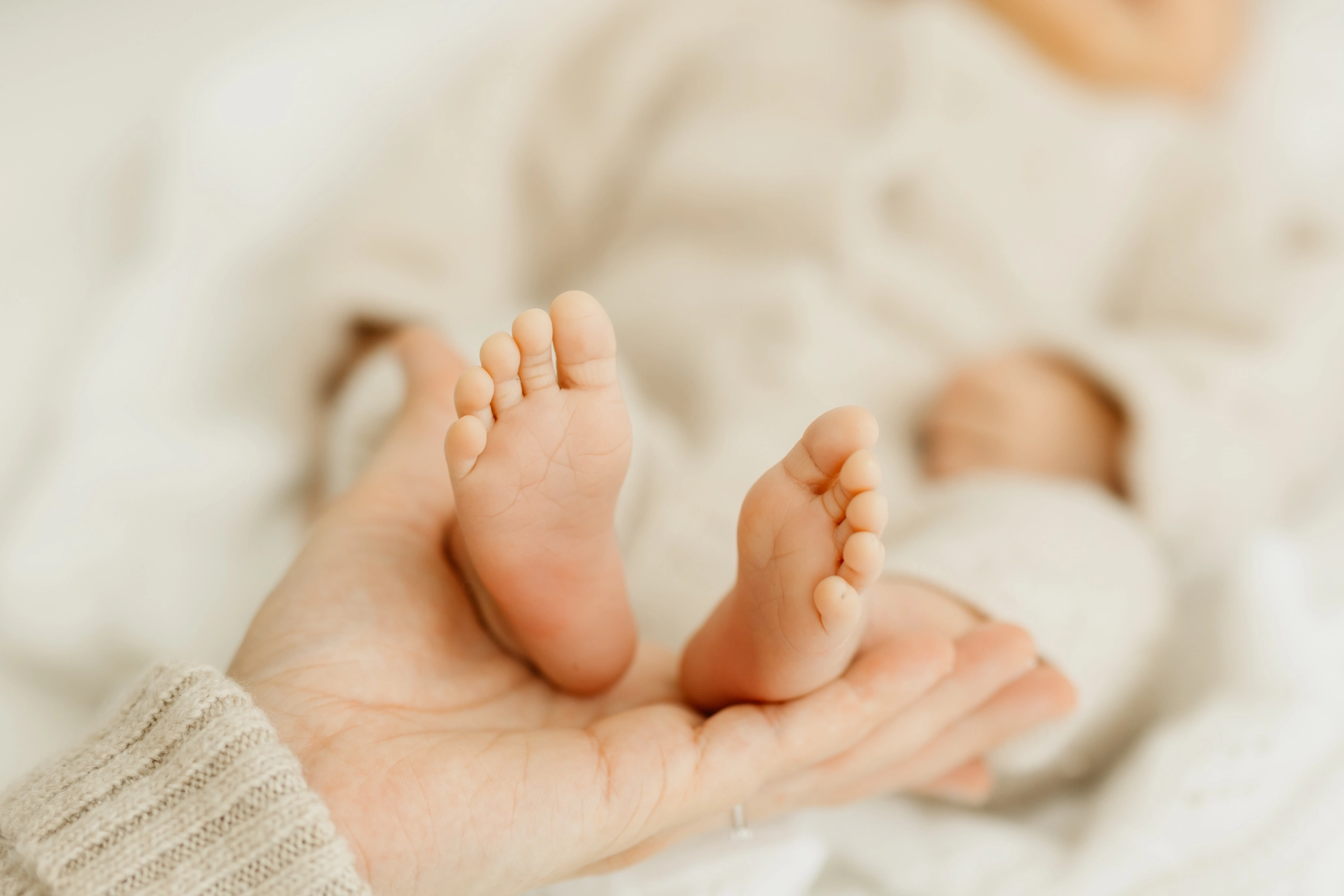 Hand der Mutter hält Babyfüße